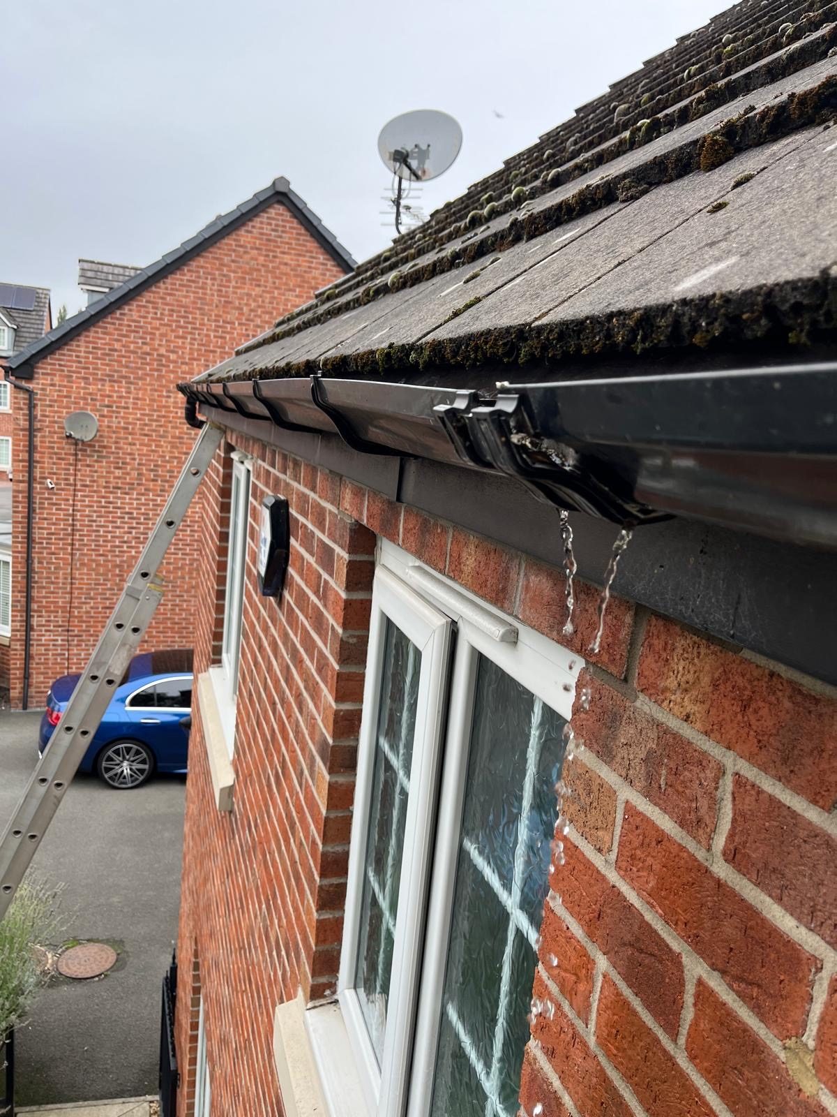 Water leaking from a gutter joint on a red-brick house
